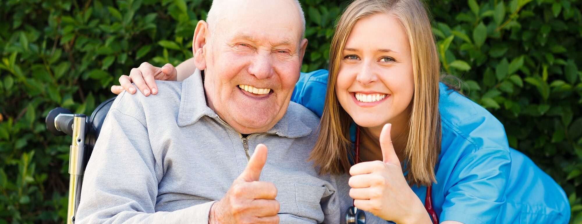 A senior and a woman outside holding a thumbs up and smiling.